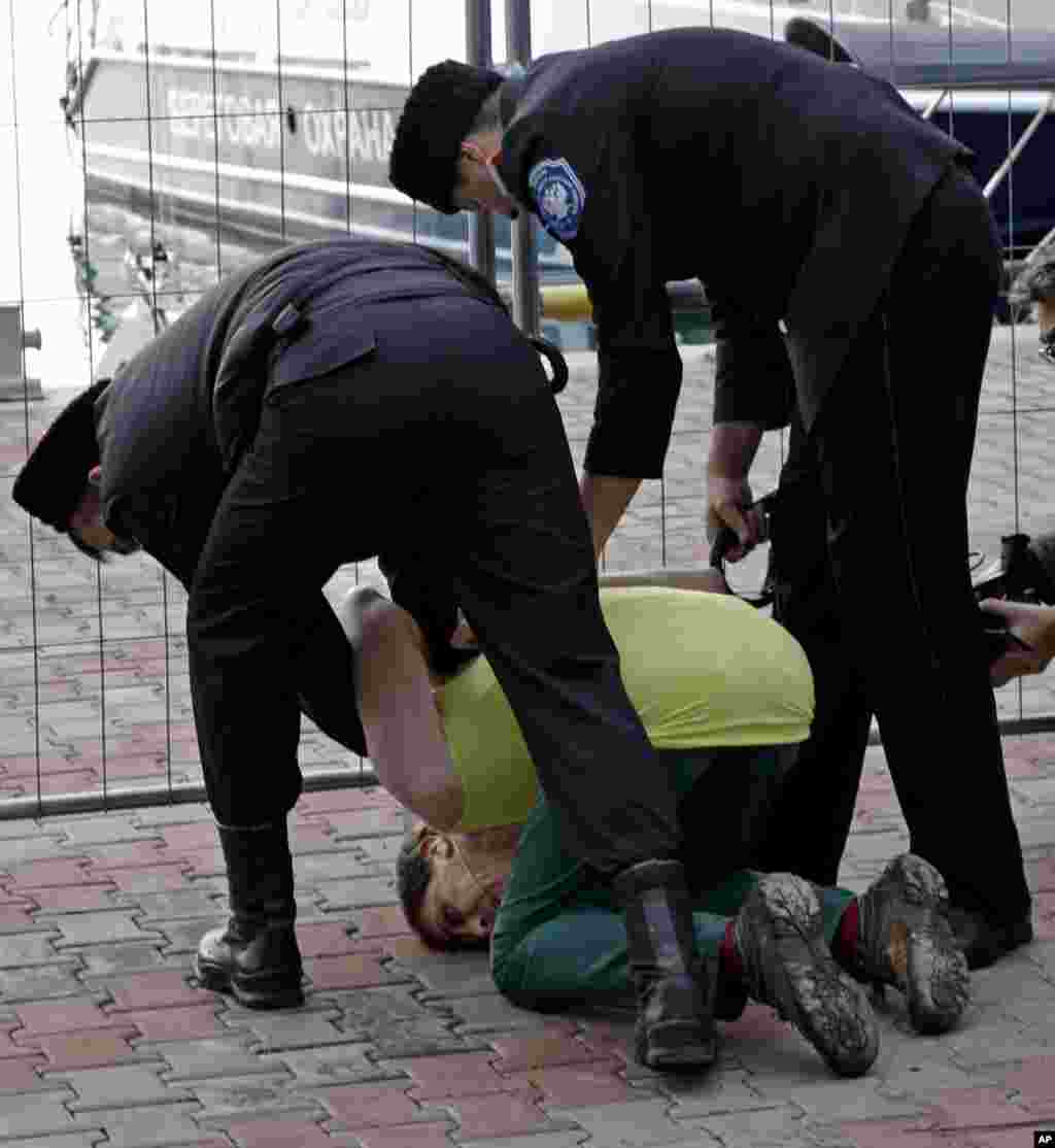 A member of Pussy Riot is restrained by Cossacks after the attack.