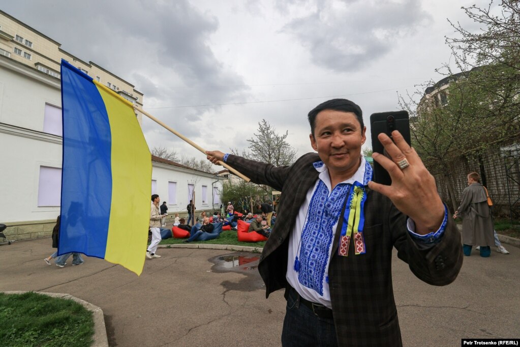 Një burrë duke pozuar për një selfie me flamurin ukrainas.