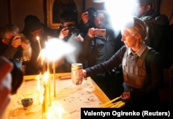 Президентка Європейської комісії Урсула фон дер Ляєн запалює свічку в церкві біля братської могили під час відвідування Бучі На Київщині, Україна, 8 квітня 2022 року