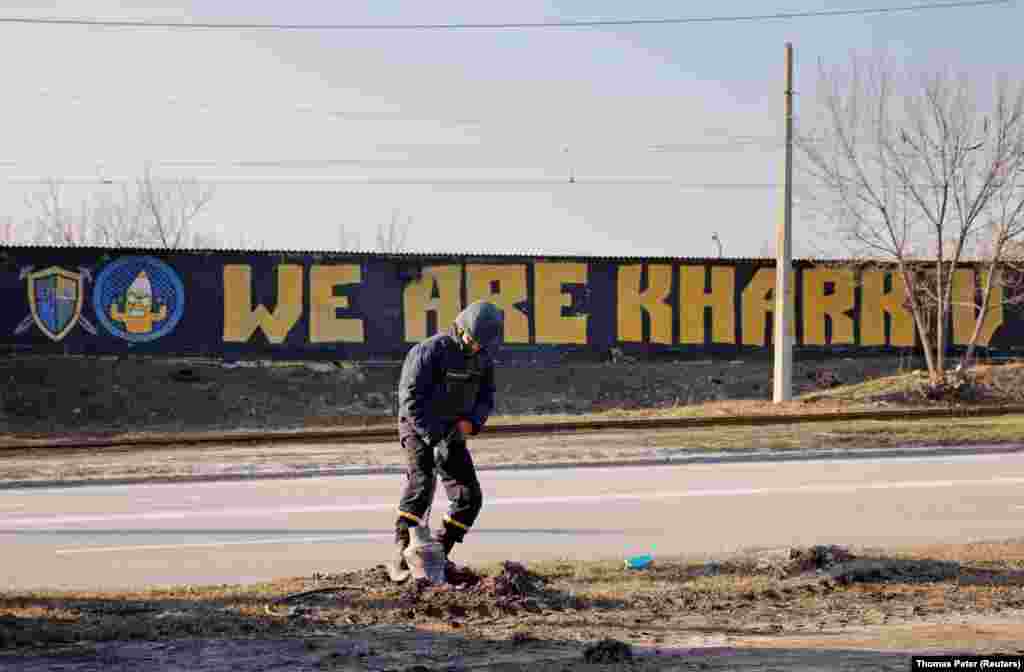 An explosives specialist pulls out a piece of a rocket lodged next to a road in the north of Kharkiv on March 24.&nbsp;