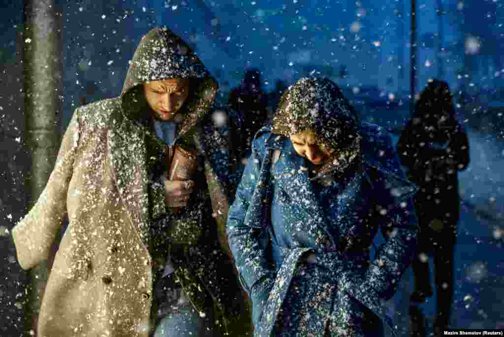 People walk in the street during a heavy snowfall in Moscow on April 6.