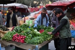 People buy vegetables at a food market in Kabul (file photo)