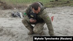 Украинский военный сапёр подбирает неразорвавшиеся части кассетной бомбы