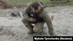 Украинский военный сапёр подбирает неразорвавшиеся части кассетной бомбы