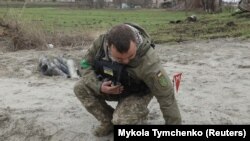 Украински военен сапьор прибира невзривена част от касетъчна бомба.