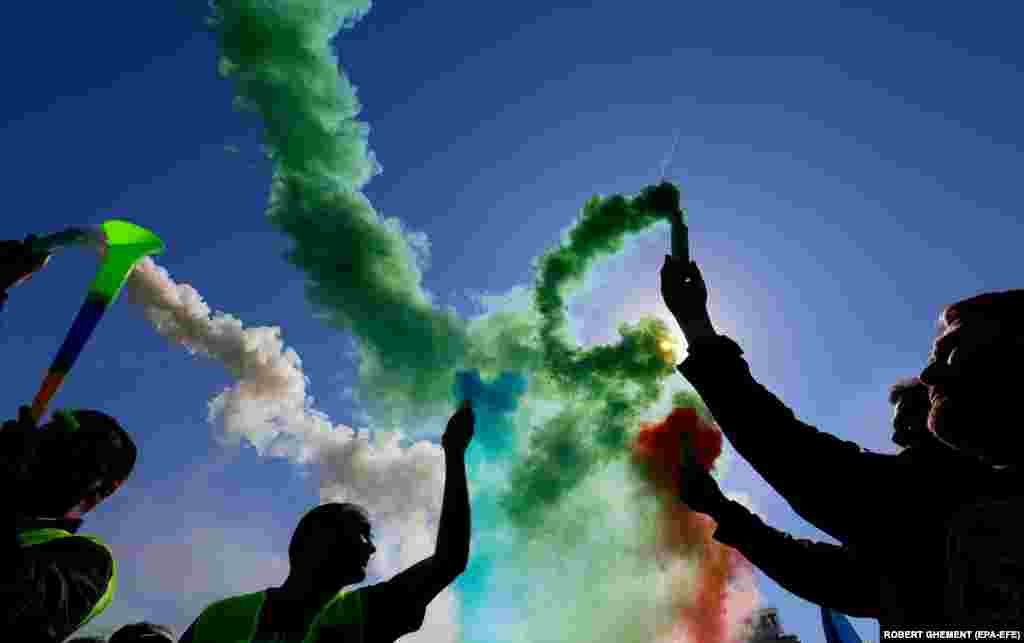 Romanian police light colored smoke flares during a confederation of trade unions protest in front of Romanian government headquarters in Bucharest. Thousands of people of trade unions from all over the country demanded measures to mitigate the effects of the war in Ukraine, to tackle the energy and food crisis, and to negotiate salaries after the economic crisis generated by the COVID-19 pandemic.