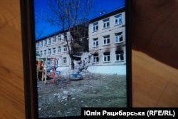 Оксана Обідченко показує фото школи №7, де вона працювала у Волновасі, після російських обстрілів