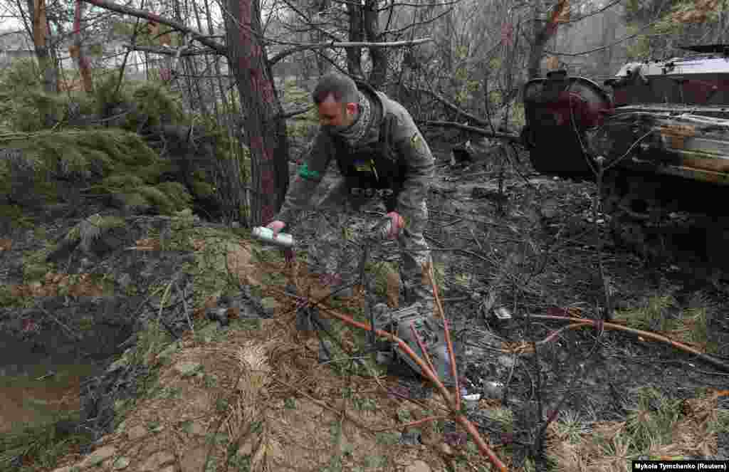 Egy utász óvatosan felszed egy kazettás bombából származó minibombát Motizsinben április 10-én. A kazettás vagy fürtös bombák olyan szerkezetek, amelyeket több tucat kisebb bombával töltöttek meg, amelyeket úgy terveztek, hogy nagy területen szóródjanak szét és a becsapódáskor robbanjanak fel. Több mint száz ország írta alá a használatukat tiltó egyezményt, de sem Ukrajna, sem Oroszország nem ratifikálta​ &nbsp; 