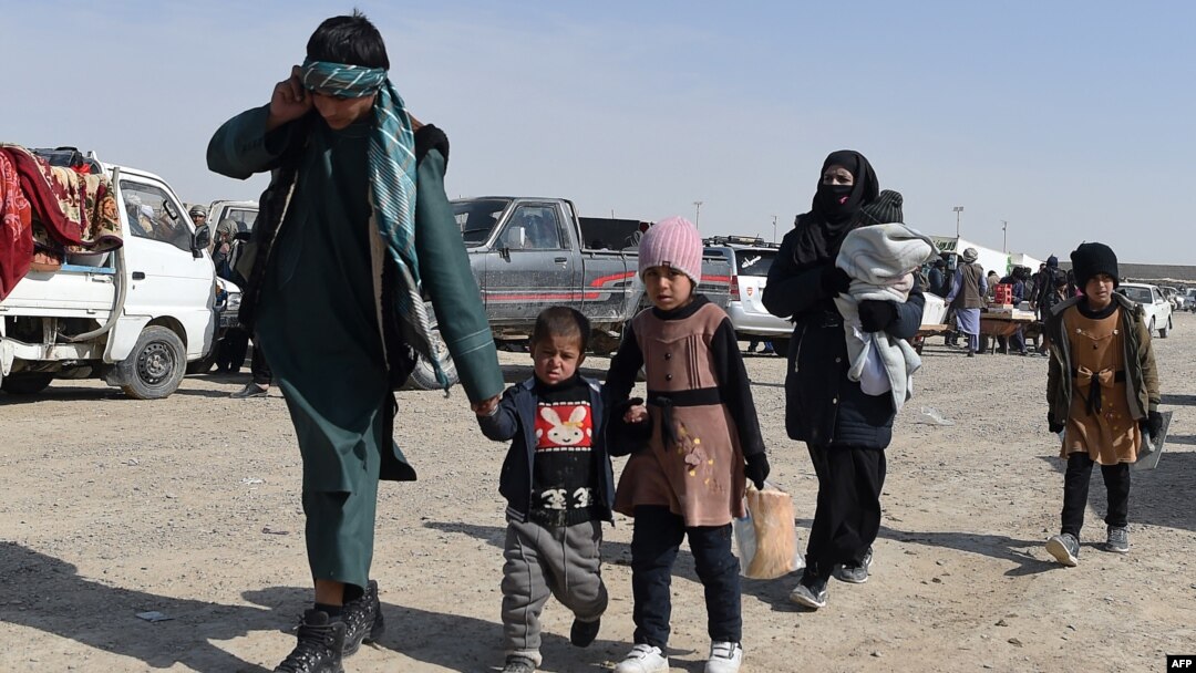 An Afghan migrant family walks in a parking lot before leaving the country in the southwestern province of Nimroz in February. 