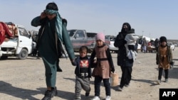 An Afghan migrant family walks in a parking lot before leaving the country in the southwestern province of Nimroz in February. 