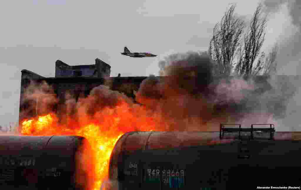 A Russian fighter jet flies above a railway junction on fire following recent shelling in the town of Shakhtarsk, near Donetsk, in Russian-controlled Ukraine.