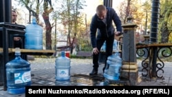 Чоловік біля одного з бюветів в Києві набирає воду