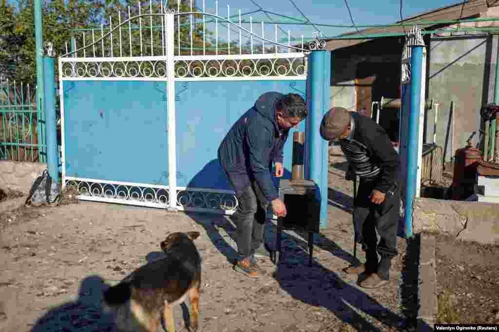 The head of a local council explains how the stoves function to a resident of Prybuzke, near the front lines of the fighting. The engineering of the stoves is based on existing designs, &quot;just improved a little bit to make it easy to use and cheaper to produce,&quot; Ramestam says.&nbsp;