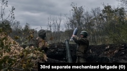 Vojnik ubacuje granatu kalibra 120 mm u minobacač, istočna ukrajinska regija Donbas, oktobar 2022.