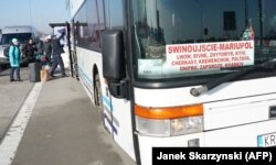 Граждане Украины перед автобусом, соединяющим польский город Свиноуйсьце с украинским городом Мариуполь, пересекают границу Украины с Польшей