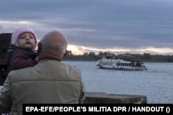 An image provided by Russian-occupation forces shows a man with a child as Kherson residents are relocated to the left bank of the Dnieper River on October 20.