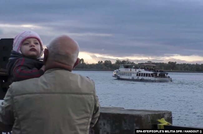 Ethnic Cleansing = An image provided by Russian-occupation forces shows a man with a child as Kherson residents are relocated to the left bank of the Dnieper River on October 20.