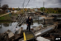 Мужчина переходит разрушенный мост в прифронтовом городе Бахмут в Донецкой области, 27 октября 2022 года