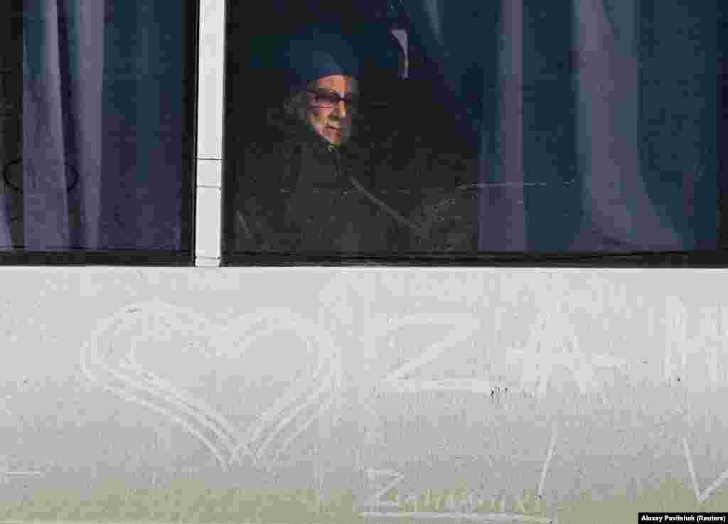 A woman looks out of a bus window as civilians evacuated from the Russian-controlled Kherson region of Ukraine arrive at a local railway station after Russian-installed officials extended an evacuation order.