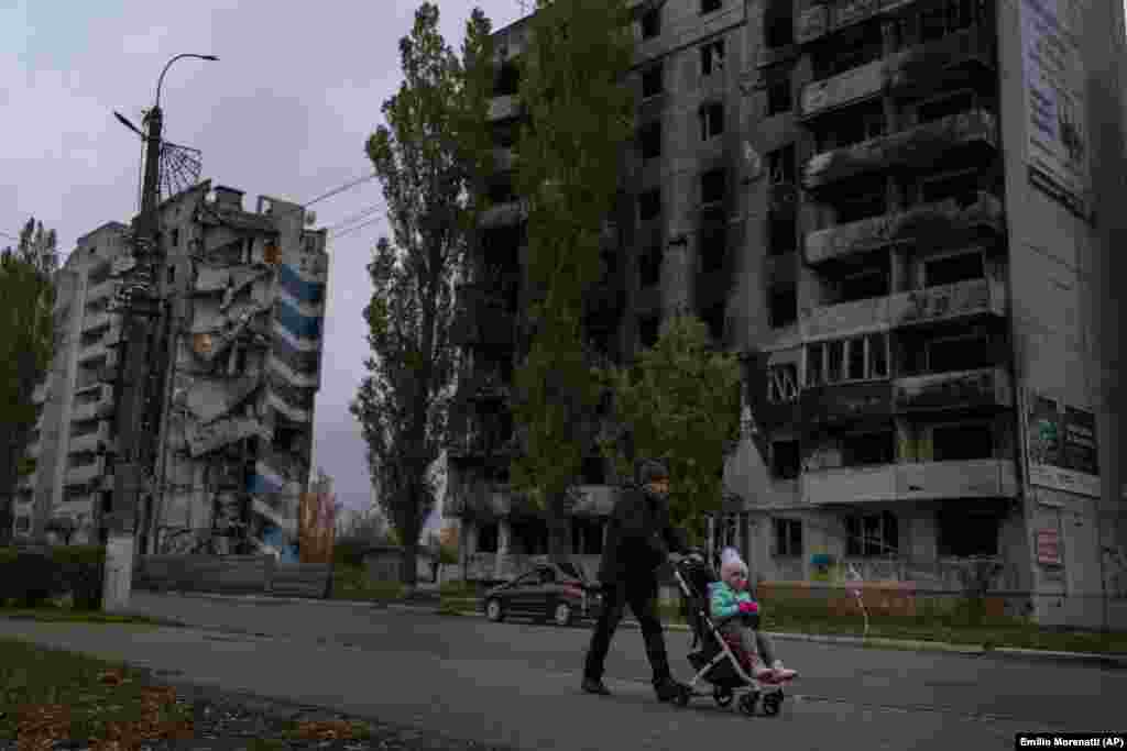 A man pushes a stroller near destroyed apartment buildings in Borodyanka. While some have power, others&nbsp;in areas without electricity and water are now bracing for a harsh winter. &nbsp;