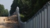 Një roje kufitare polake patrullon zonën e një muri metalik të sapondërtuar në kufirin midis Polonisë dhe Bjellorusisë.