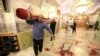Munkások takarítják fel a véres támadás nyomait a sirázi síita szent helyen 2022. október 26-án