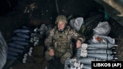 Un soldat ucrainean stă la adăpost, pregătindu-se să tragă cu mortiera asupra pozițiilor rusești în Bahmut, regiunea Donețk, Ucraina, vineri, 21 octombrie 2022. 