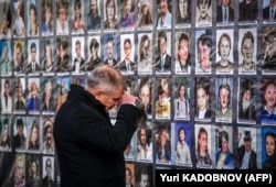 A man stands before photos of victims of the Nord-Ost hostage crisis at a commemoration ceremony in 2022