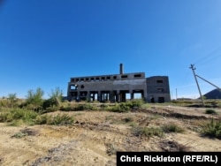 The carcass of the village's disused power plant stares across the steppe.