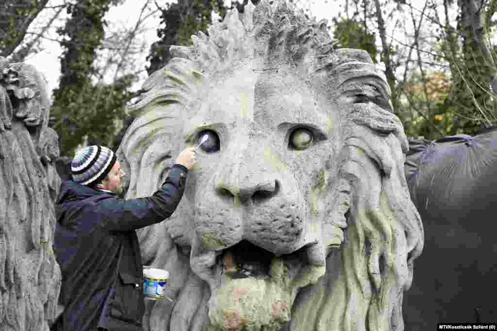 Sculpture restorer Balazs Szemerey-Kiss works on one of the lions of the Chain Bridge in November 2021.