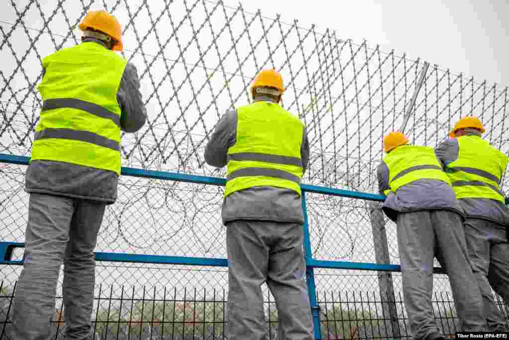 Hungarian prisoners attach razor wire to the top of a fence on the border with Serbia in Roszke, southern Hungary, on October 28. The newly heightened fence was first constructed in 2015 amid a wave of migrants from the Middle East attempting to enter the European Union. &nbsp; &nbsp;