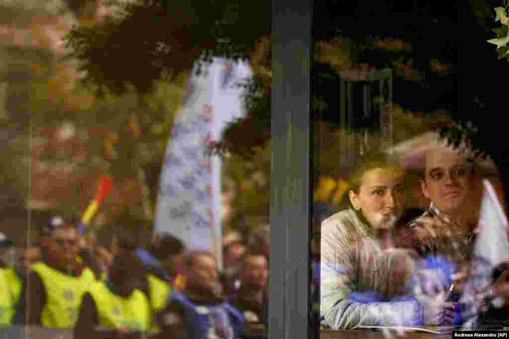 People watch from inside a coffee shop in the Romanian capital, Bucharest, as trade union members rally during a protest dubbed &quot;The Anti-Poverty March,&quot; which called for salary and pension increases as well as government-controlled prices for energy and other basic commodities.&nbsp;