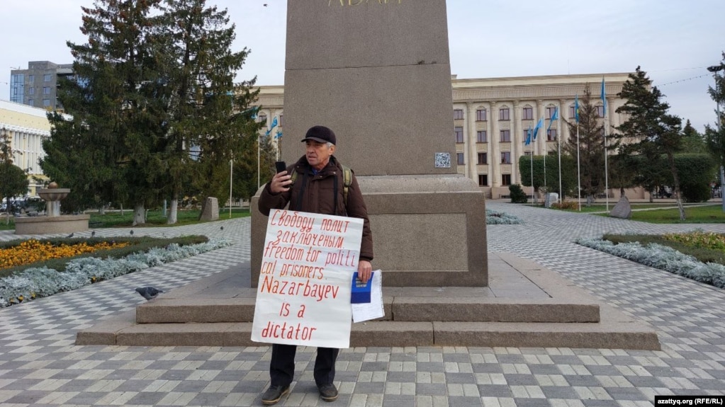 Гражданский активист Бекболат Утебаев на площади с плакатом «Свободу политзаключенным. Freedom for political prisoners. Nazarbayev is a dictator». Уральск, 28 октября 2022 года