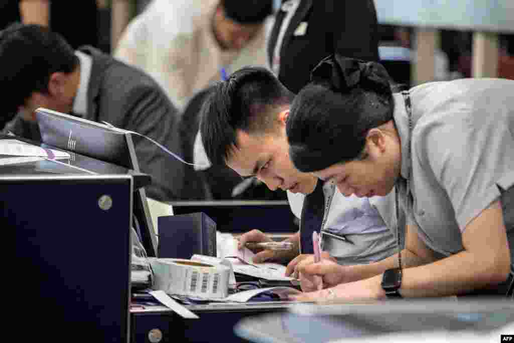 Airport staff at Hong Kong International Airport manually check in passengers.