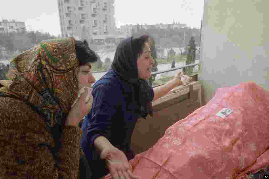 Two Azerbaijani women overcome with grief next to the body of a relative in Baku on January 28.