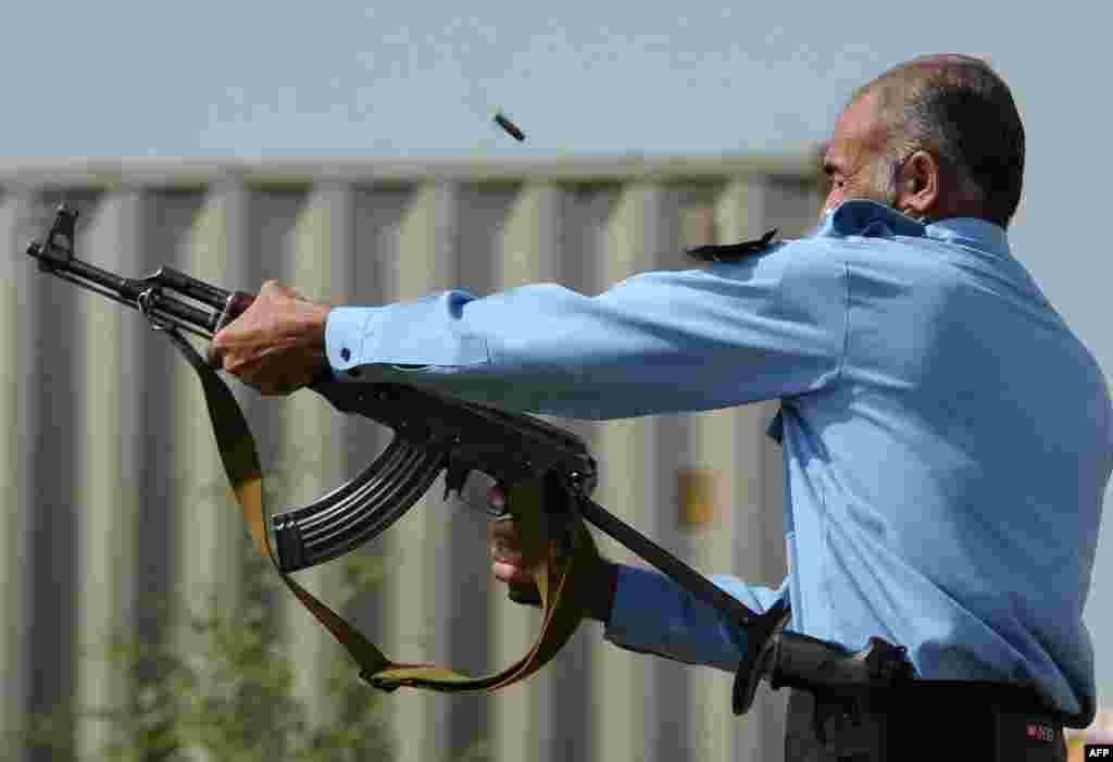 A Pakistani policeman fires an automatic weapon at demonstrators.