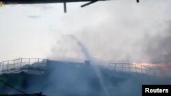 Pompieruii sting un incendiu declanșat de un atac rusescla un depozit din Nikolaev, 2 august 2022. Stop-cadru dintr-o înregistrare video pusă la dispoziție de Serviciul de stat pentru urgențe din Ucraina.