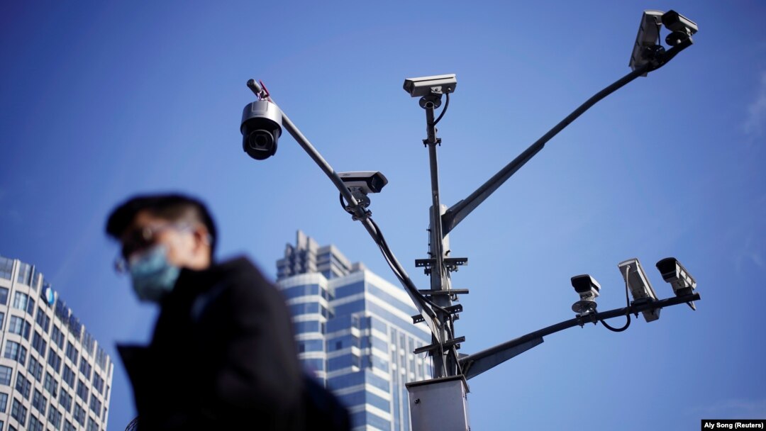 A man wearing a face mask walks past surveillance cameras following the COVID-19 outbreak in Shanghai, China, in 2021.