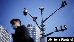 A man wearing a face mask walks past surveillance cameras following the COVID-19 outbreak in Shanghai, China, in 2021.