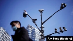 Мужчина в маске на фоне камер видеонаблюдения в Китае