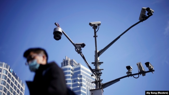 A man wearing a face mask walks past surveillance cameras following the COVID-19 outbreak in Shanghai, China, in 2021.