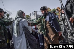 "Талибан" өкілдері әйел құқығын қорғау акциясына шыққан адамның кеудесінен итеріп, тоқтатып тұр. Кабул, 21 қазан 2021 жыл.