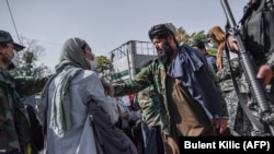 A Taliban militant tries to stop a woman from protesting at a march in Kabul on October 21.