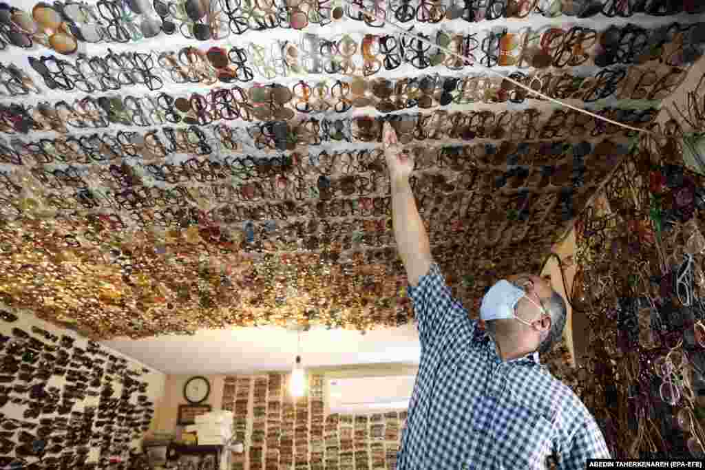 Jafar Mohaghegh, the owner of the Mohaghegh eyewear store, adjusts eyeglasses on the ceiling of his store in Tehran. The store is famous for the way it is designed and decorated.