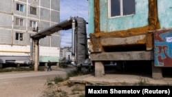 A man walks past buildings that are constructed on concrete piles to prevent permafrost from thawing, in Yakutsk, Russia, September 4, 2021.