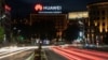 Cars drive past a Huawei logo on a building in central Belgrade.