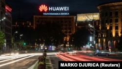 Cars drive past a Huawei logo on a building in central Belgrade.