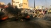 Oamenii se adună în stradă, în timp ce flăcările și fumul se ridică din străzile Kartoumului, Sudan, în urma unei posibile lovituri de stat, 25 octombrie 2021.
