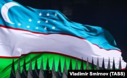 Uzbek President Shavkat Mirziyoev is dwarfed by the national flag during a postelection rally on October 25.