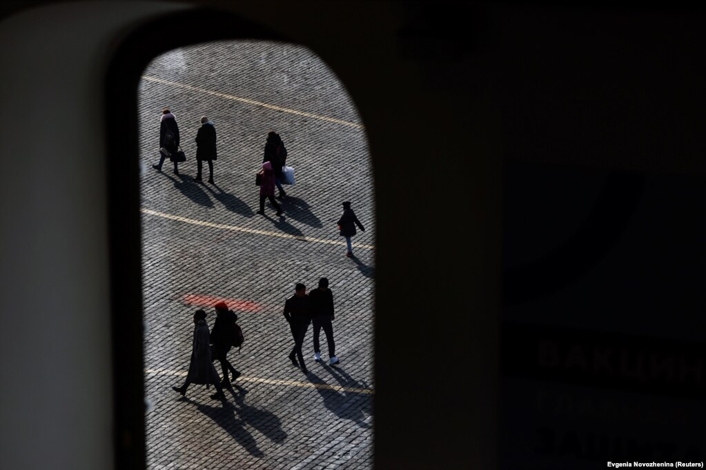 People walking across Red Square in Moscow are seen through the window of a vaccination center in the GUM state department store amid a surge in COVID-19 infections.